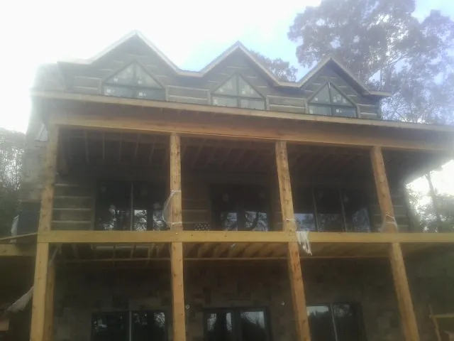 Dormers and porch framing on a large log home under construction — Roof Coating work by our crew in Marana