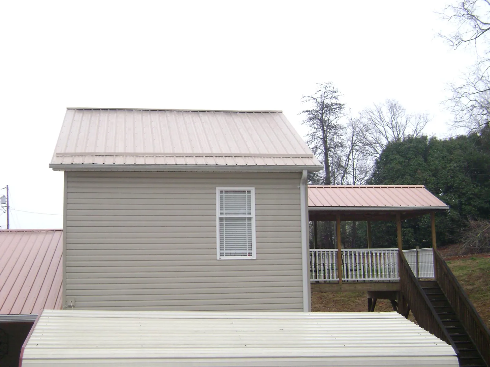 Tan metal roofs on a two story addition and attached porch, from a Roof Replacement job in Marana