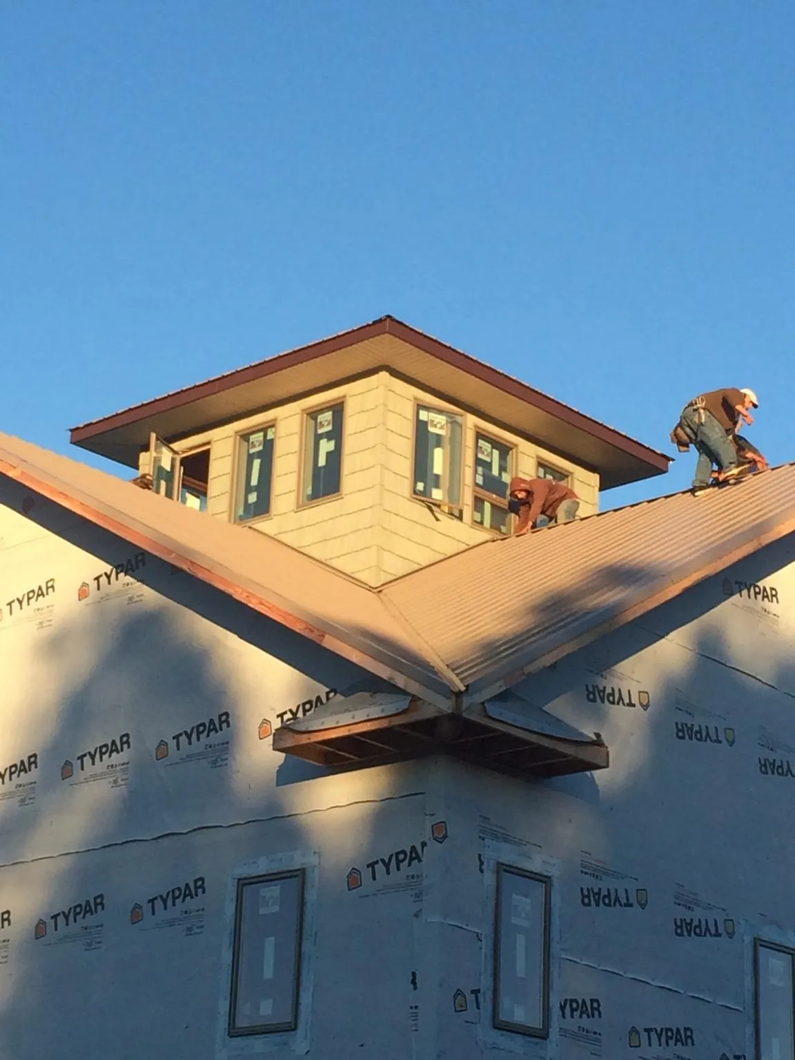 Roofers working around a rooftop cupola on a new metal roof at sunset — Roof Waterproofing in Marana by Roofing Brothers